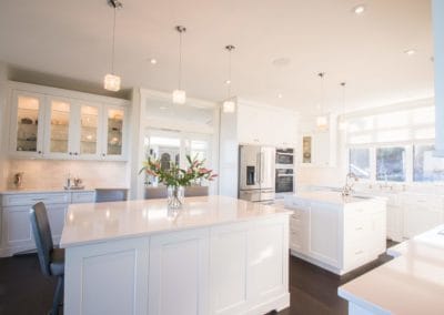 Complete view of kitchen area with two islands and double ovens in custom home