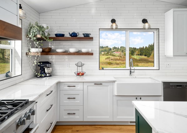 White cabinetry and subway tile backsplash with floating shelves, windows and accent lights