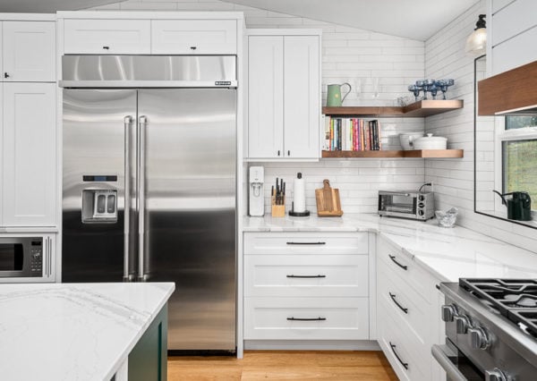 Stainless steel appliances, white cabinetry and floating shelving in kitchen