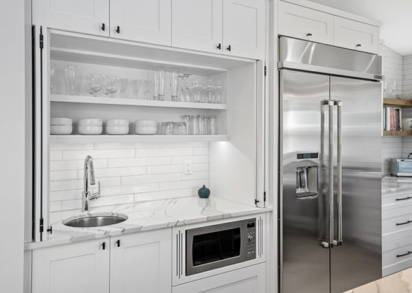 Hidden sink and counter in white shaker tile cabinetry