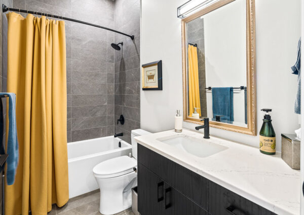 Guest bathroom, gray tile, black vanity, yellow shower curtain