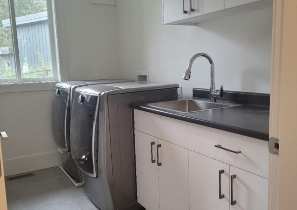 White cabinetry and black countertop in laundry room