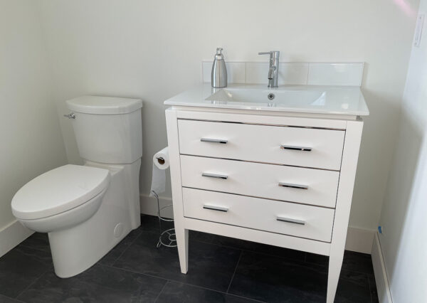 Powder room with dark flooring and white vanity