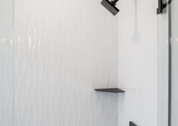 White tiled shower with black faucet