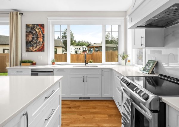 Kitchen sink view in white kitchen with wood floors