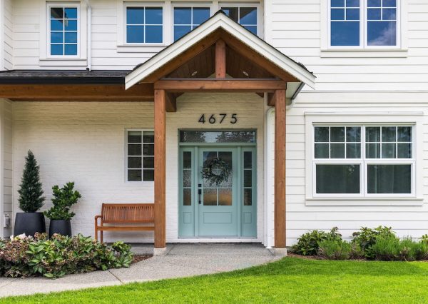 Blue front door with white brick exterior and wood beam covered entrance