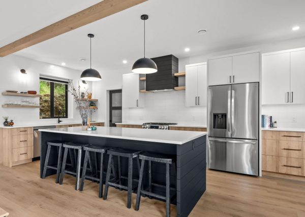 White, wood and black cabinetry with black hardware and stainless steel appliances in custom designed kitchen