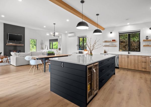 Black shiplap kitchen island with wood flooring and wood cabinetry with white countertops