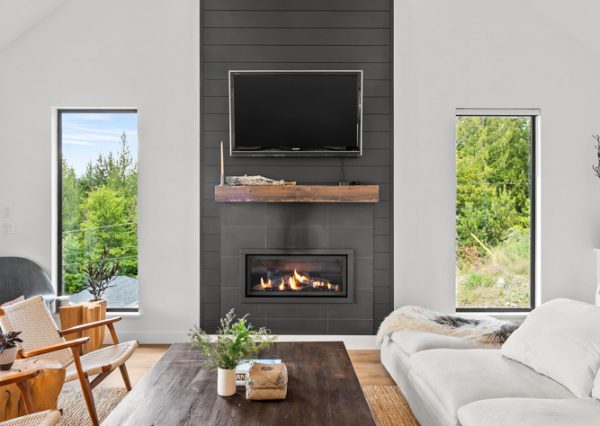 Living room with black shiplap fireplace, white walls and vaulted ceiling