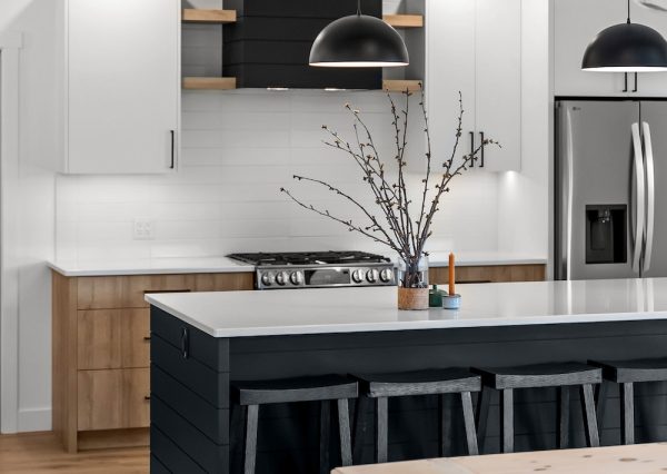 Wood beam on ceiling in kitchen with black shiplap hood fan and island