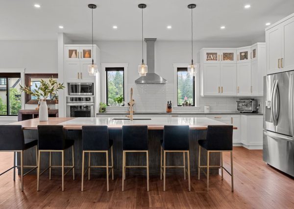 Large kitchen in custom home with white and wood cabinetry and stainless steel appliances