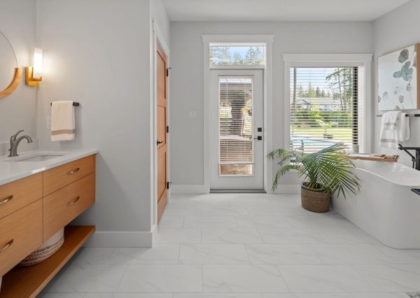 Primary ensuite with wood vanity, freestanding bathtub and water closet