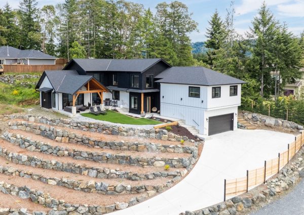 Custom home in Shawnigan Lake on a hilltop with concrete driveway and retaining walls.