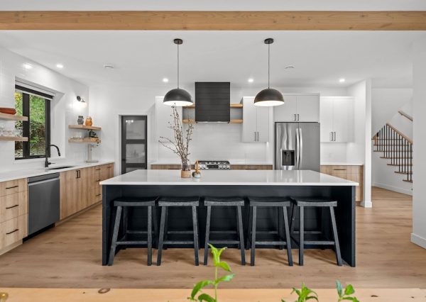 Custom kitchen with wood flooring and features wood, black and white cabinetry.