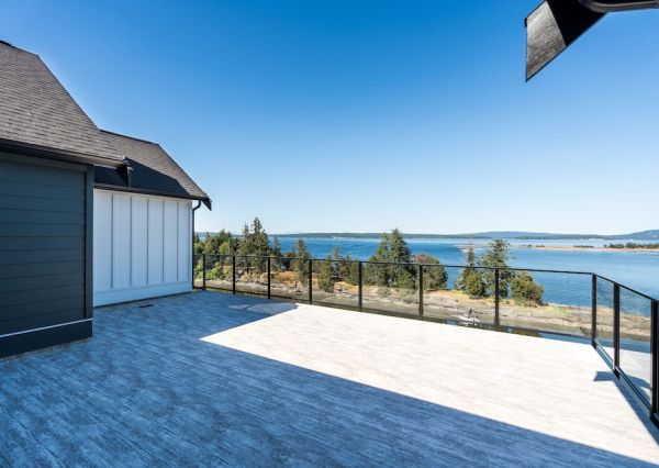 Expansive upper-level deck with glass railings overlooking the ocean and surrounding islands.