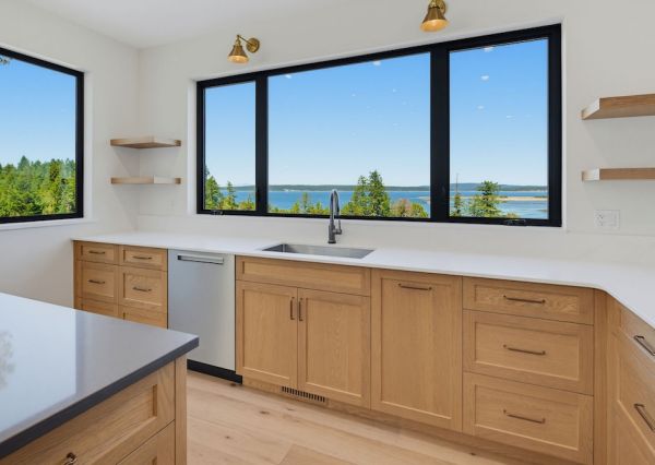 Ocean views through large black-framed windows in The Inlet kitchen
