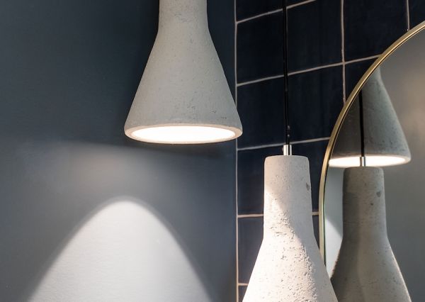 Sculptural pendant lights, round brass mirror and glossy dark tile create a dramatic powder room.