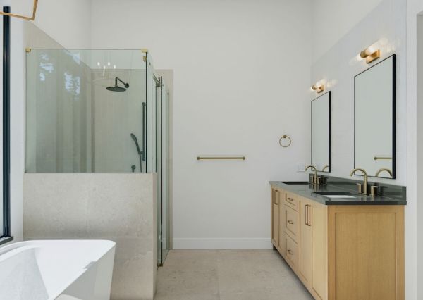 Light-filled primary bathroom with skylights, freestanding tub, glass shower and natural wood double vanity.