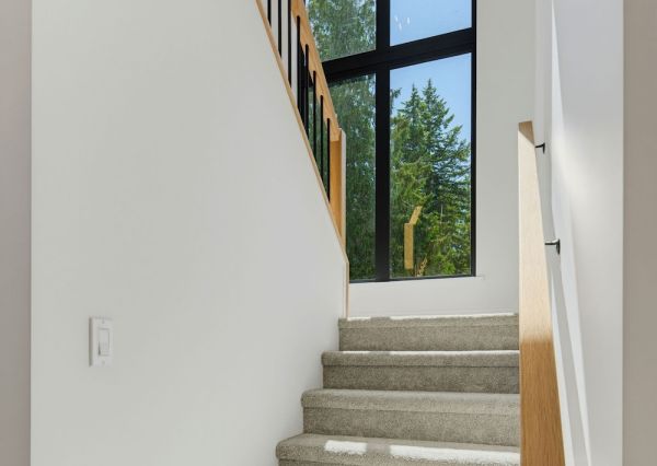 Custom staircase with oak handrails, black metal balusters and a dramatic floor-to-ceiling window.